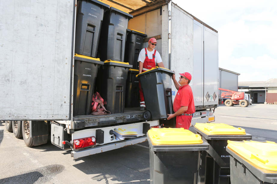 A szolgáltató munkatársai, Erdélyi Tamás és Hartai László kiosztandó sárga fedelű edényeket pakolnak fel a kamionra.